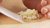 Finely chopped garlic being remove from the work surface