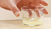 A glass of lemon juice being removed from a work surface
