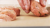 Raw meatballs being placed on a baking tray laid with greaseproof paper
