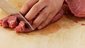Rindfleischscheiben in Würfel schneiden