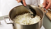 Onions being placed in a pot and fried