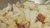 Onions being fried with diced bacon