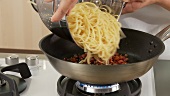 Spaghetti zu den gebratenen Speckwürfeln geben