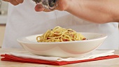 Spaghetti alla Carbonara being sprinkled with pepper