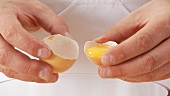 Egg yolk being poured into a bowl