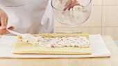 Strawberry cream filling being spread on a layer of sponge cake