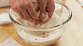 Fresh yeast being crumbled and added to a well in flour