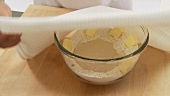 Starter dough in a bowl being covered and left to rise