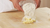 Flour and sugar being added to chopped butter