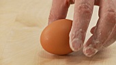 Hand entnimmt ein Ei