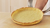 Baked shortcrust tart base being removed from the dish