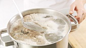 Foam being scooped off the top of beef stock