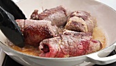 Beef roulade being turned in hot oil