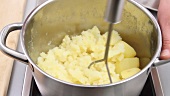 Cooked potatoes being mashed