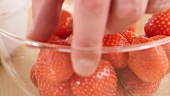 A hand taking a strawberry