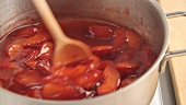 Plum compote being stirred in a pot