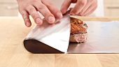 Fried duck breast being wrapped in aluminium foil