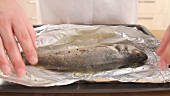 Foil being removed from cooked bass