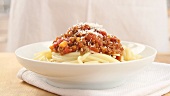 Sprinkling spaghetti Bolognese with Parmesan