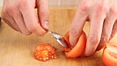 Peeled tomatoes being halved and deseeded