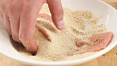 Veal escalope being turned in breadcrumbs