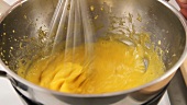 Egg yolk cream being beaten in a bain marie
