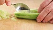 A peeled cucumber being deseeded