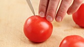 Tomatoes being scored with a knife
