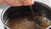 Fat being removed from gravy with a ladle
