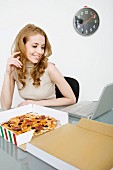 Young businesswoman eating pizza during lunch break