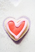 A red and white, heart-shaped marzipan biscuit with sugar