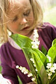 A little girl holding a bunch of lily of the valley