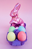 A chocolate Easter bunny and coloured eggs in an egg box