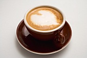 Cappuccino mit Milchschaumherz in brauner Tasse