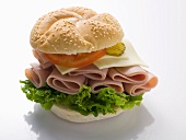 A sesame seed roll with ham, cheese, tomato and gherkins
