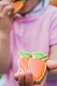 A child holding carrot biscuits