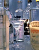Wodka in einem Glas vor verschiedenen Wodkaflaschen