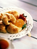 Croissants mit Orangenmarmelade, Erdbeere & Messer auf Teller