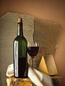 Glas & Flasche Rotwein mit einem Stück Käse & Serviette