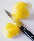 Zitronenschale, Messer und halb geschälte Zitrone