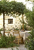 Italienisch gedeckter Tisch im Garten an der Hauswand