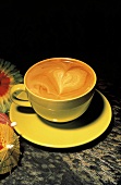 Kaffee in gelber Tasse mit dekorativem Milchschaum