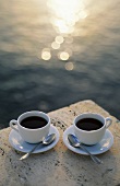 Zwei Kaffeetassen vor Sonnenuntergang am Meer