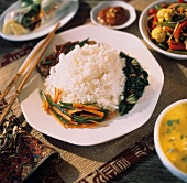 Weisser Reis umringt von Gemüse auf Teller mit Stäbchen