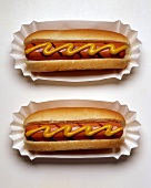 Zwei Hot Dogs mit Senf auf Papptellern