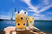 A Pitcher and Glass of Lemonade on a table Overlooking a Lake