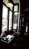Frau mit Arbeitsunterlagen & Kaffee am Tisch in einem Café
