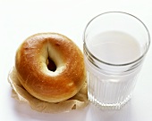 Ein einfaches Bagel neben einem Glas Milch
