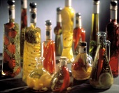 Verschiedene Essigflaschen mit eingelegtem Gemüse, Kräutern