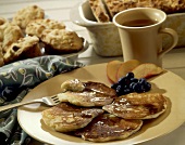 Pancakes mit Ahornsirup auf Teller; Tee
